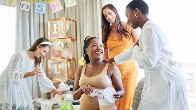 Mom-to-be smiles as friends gather around for her baby shower