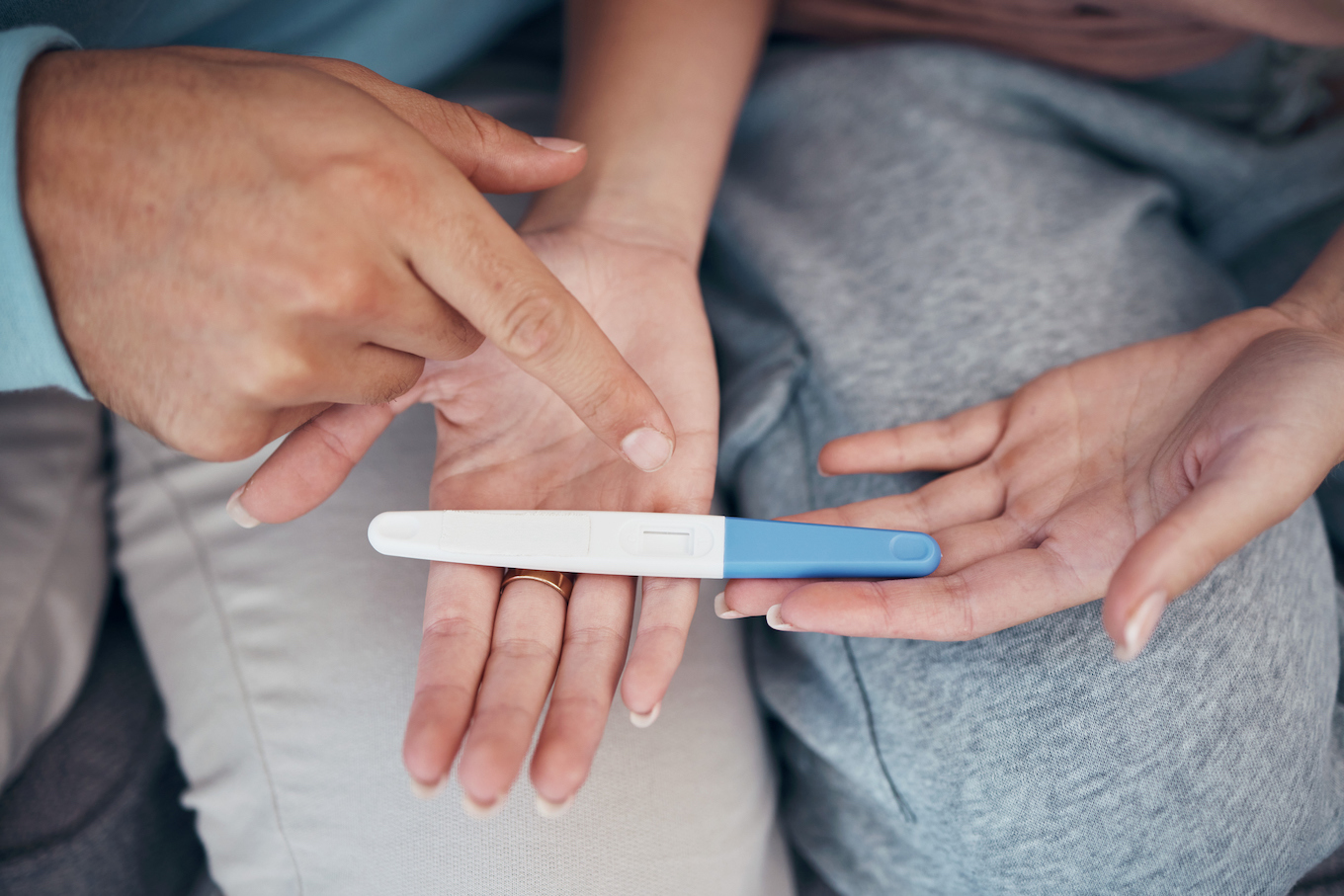 couple's hands and closeup of pregnancy test