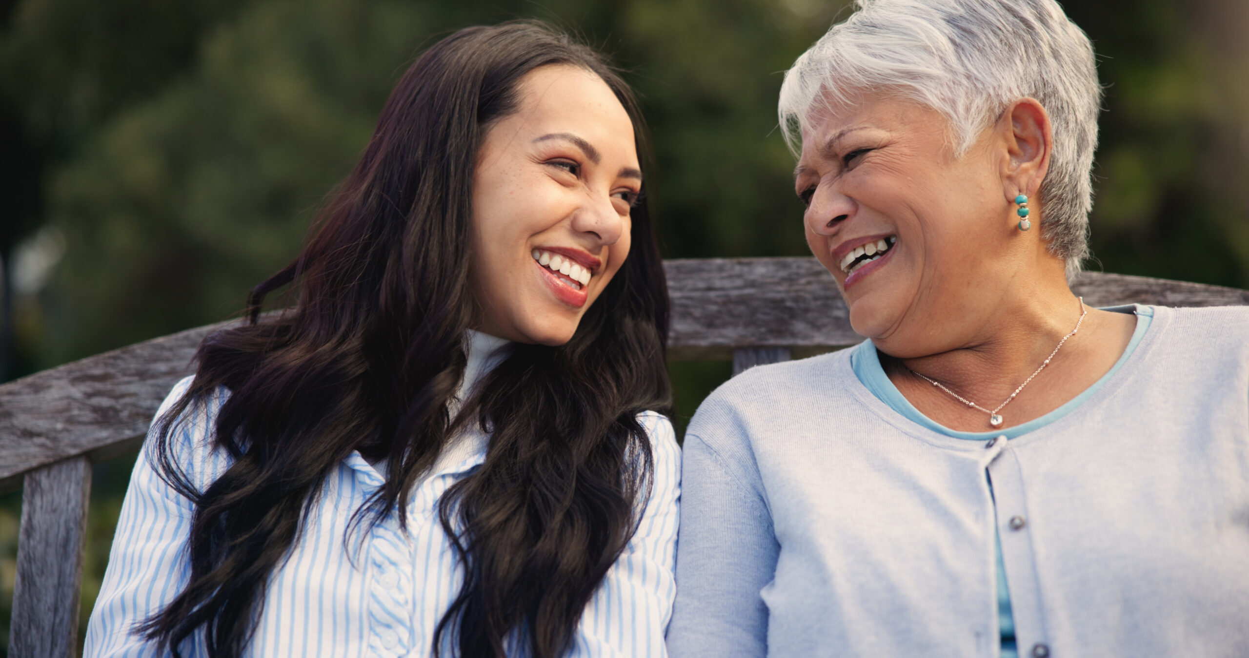 Happy, mature and mother with woman on bench, nature and bonding for laugh on retirement. Senior person, parent and older daughter for leisure together in park, care and love for funny joke in garden