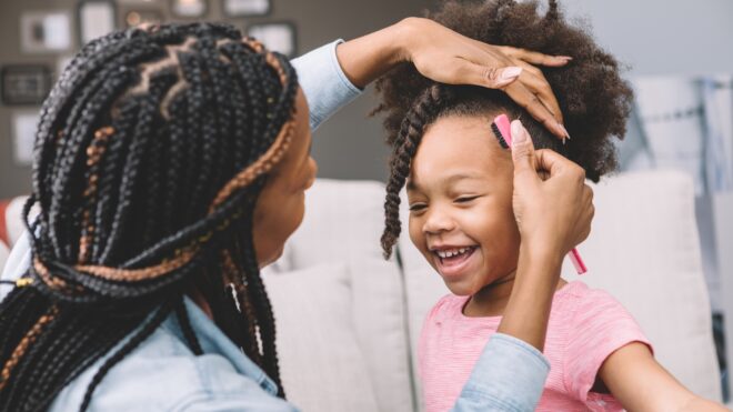 Little girl getting her hair twisted by her mom.
