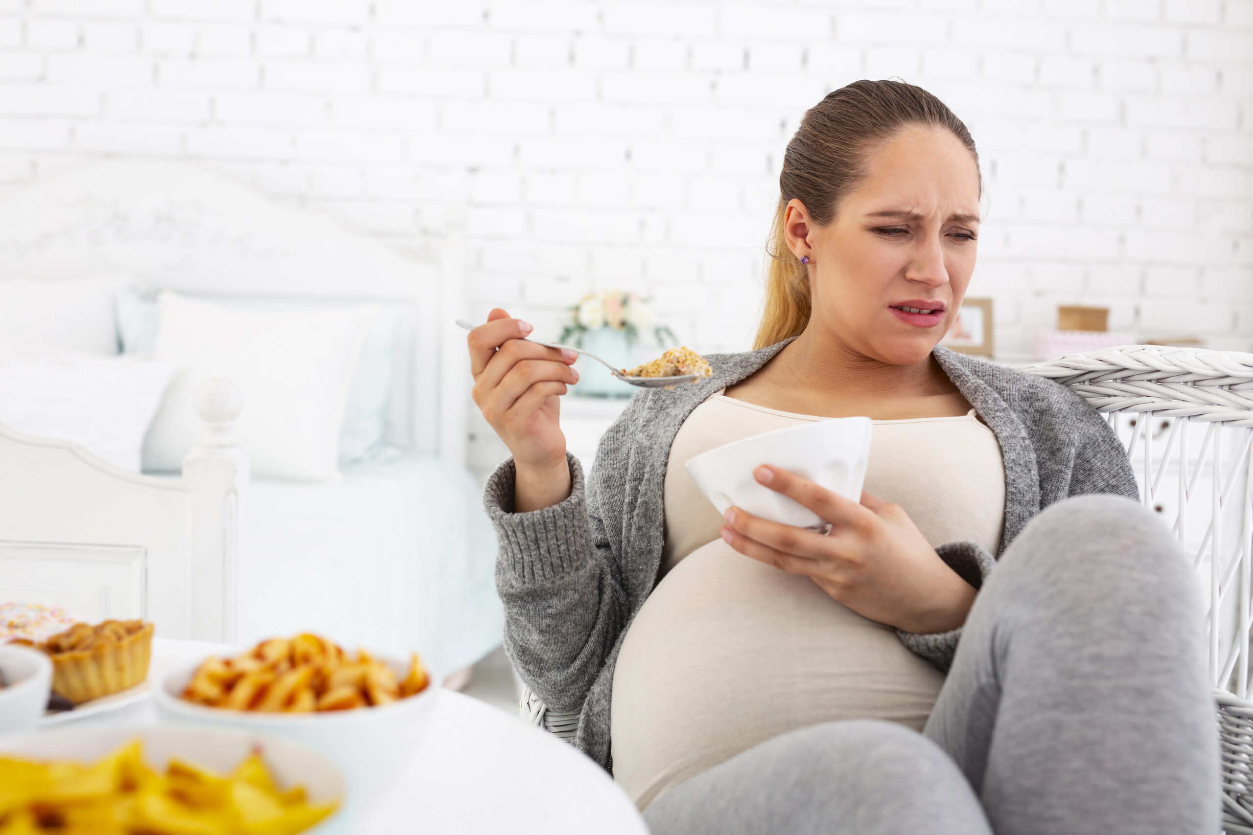 Discontented pregnant woman chewing granola
