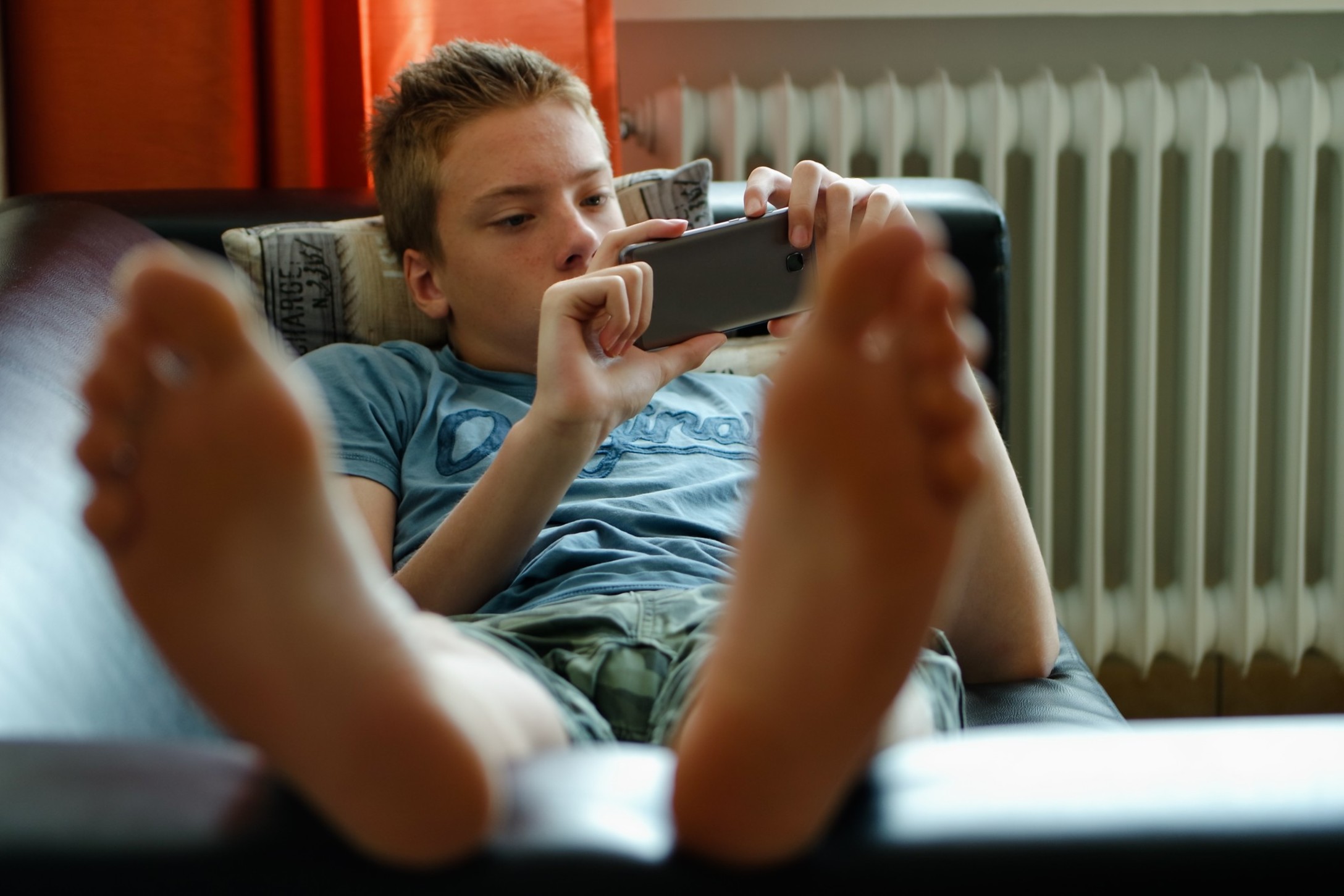 teenager-boy-laying-on-the-couch-and-using-mobile-phone_t20_V7ZNR7-2.jpg